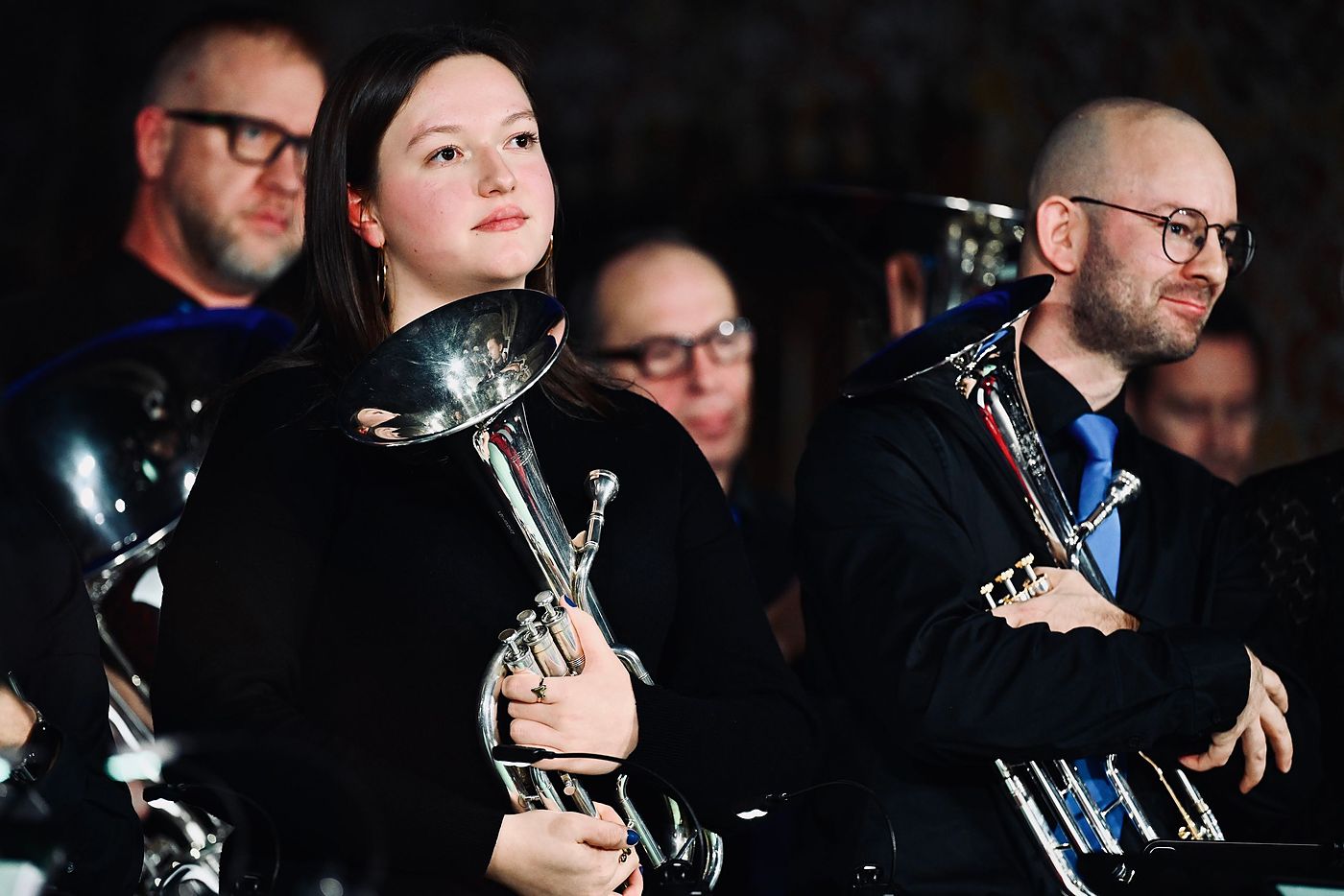 Drie muzikanten van Brass Friends Lembeek luisteren met hun instrument in de hand